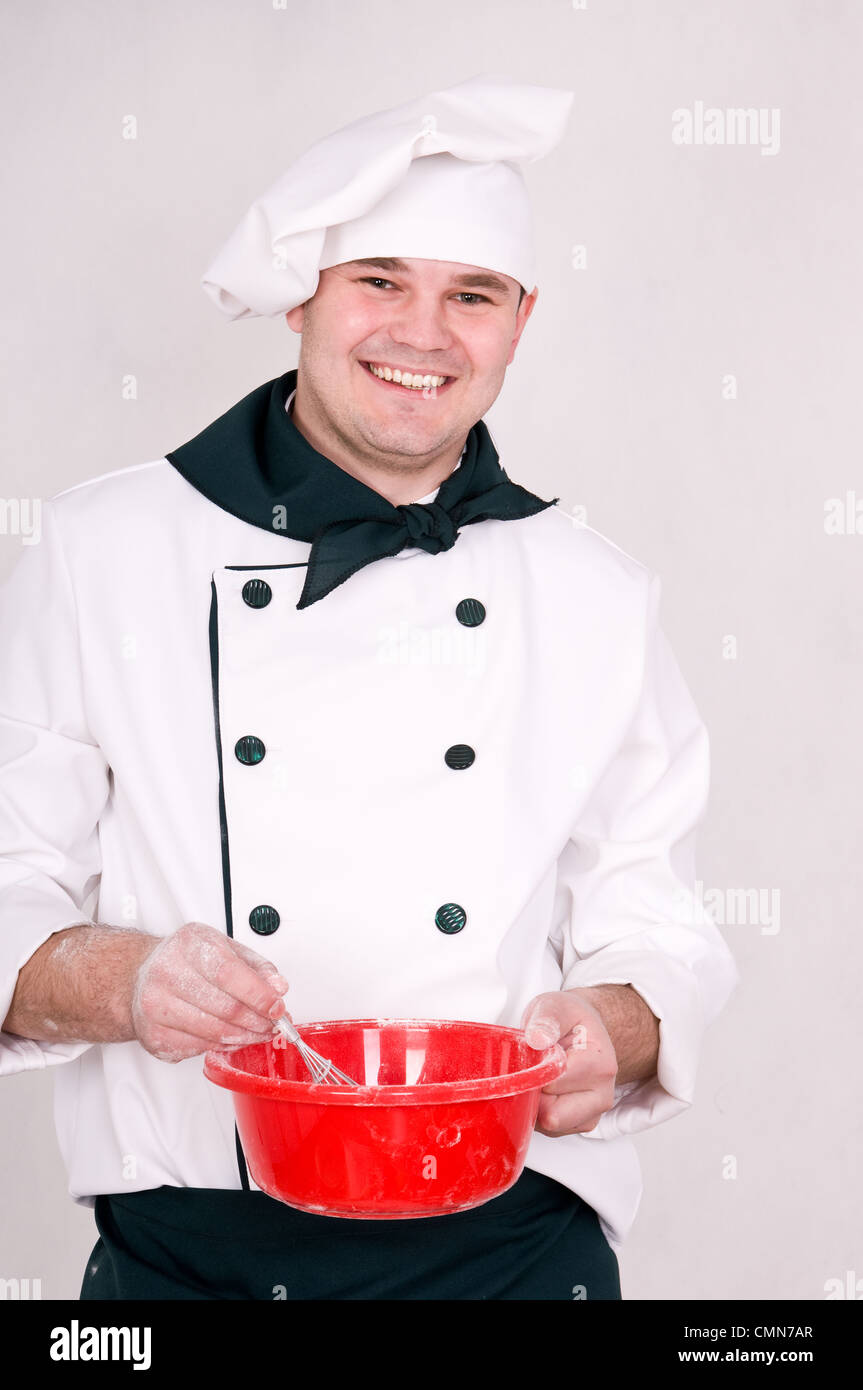 lächelnde Koch mischt den Teig in eine Schüssel geben Stockfoto