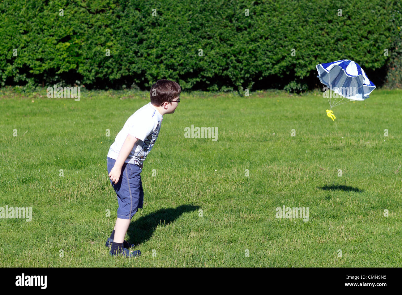 zehn Jahre alter Junge spielt mit seinem Fallschirm Spielzeug im park Stockfoto