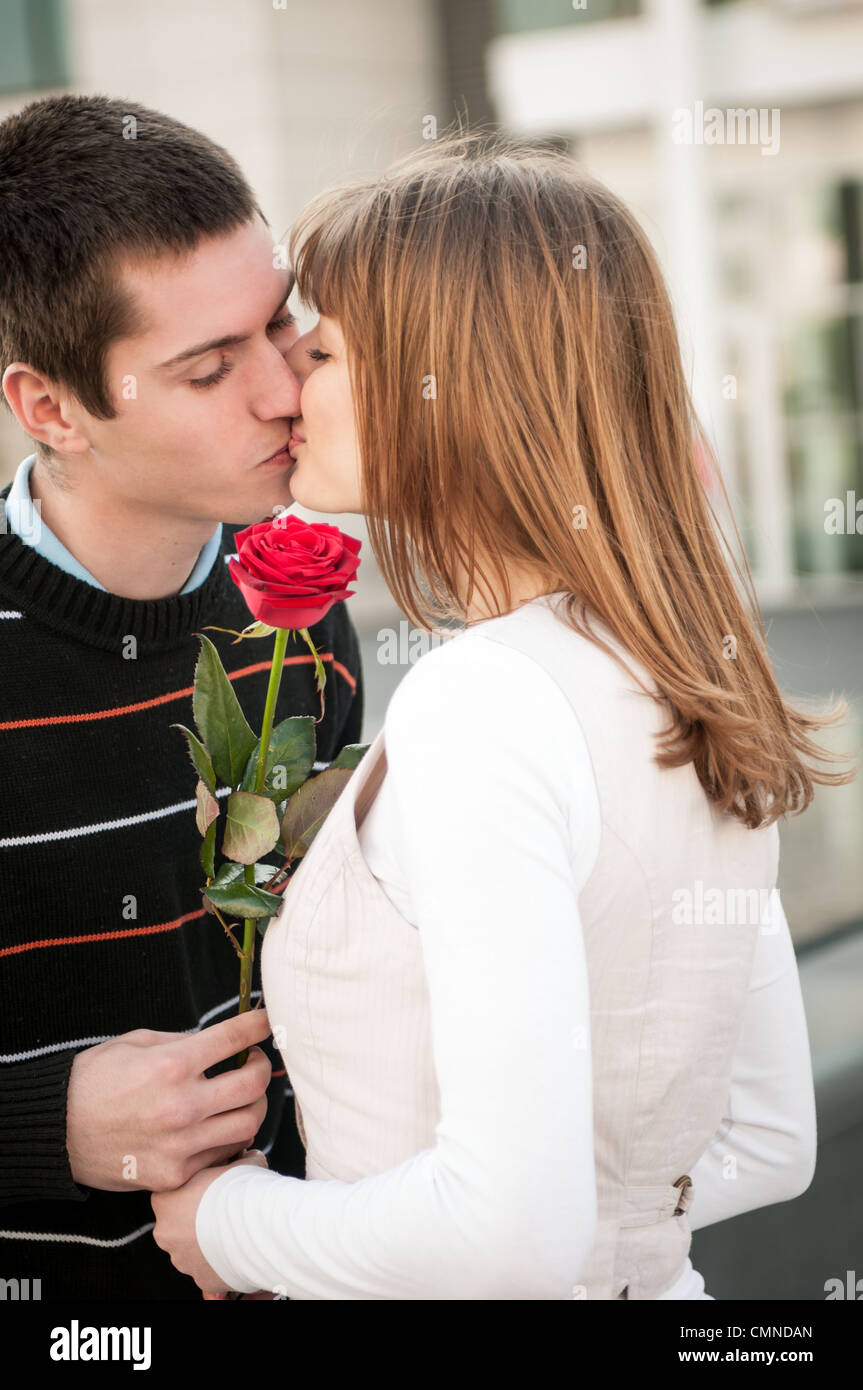 Junger Mann, die Übergabe einer Blume (rote Rose) an Frau - outdoor-Lifestyle-Szene Stockfoto