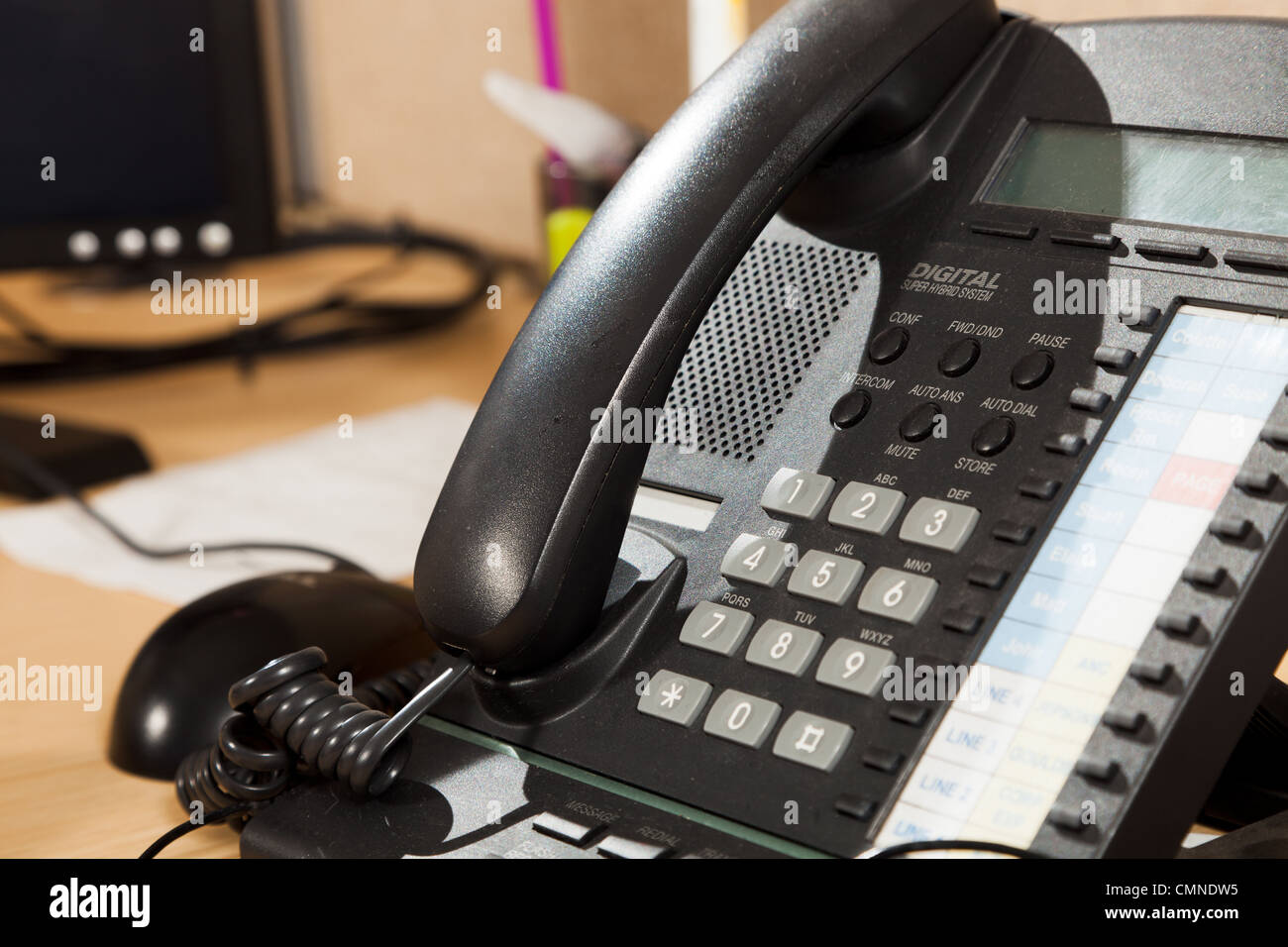 Telefonhörer auf Docking-Station mit anderen Bürogeräten hinter. Stockfoto