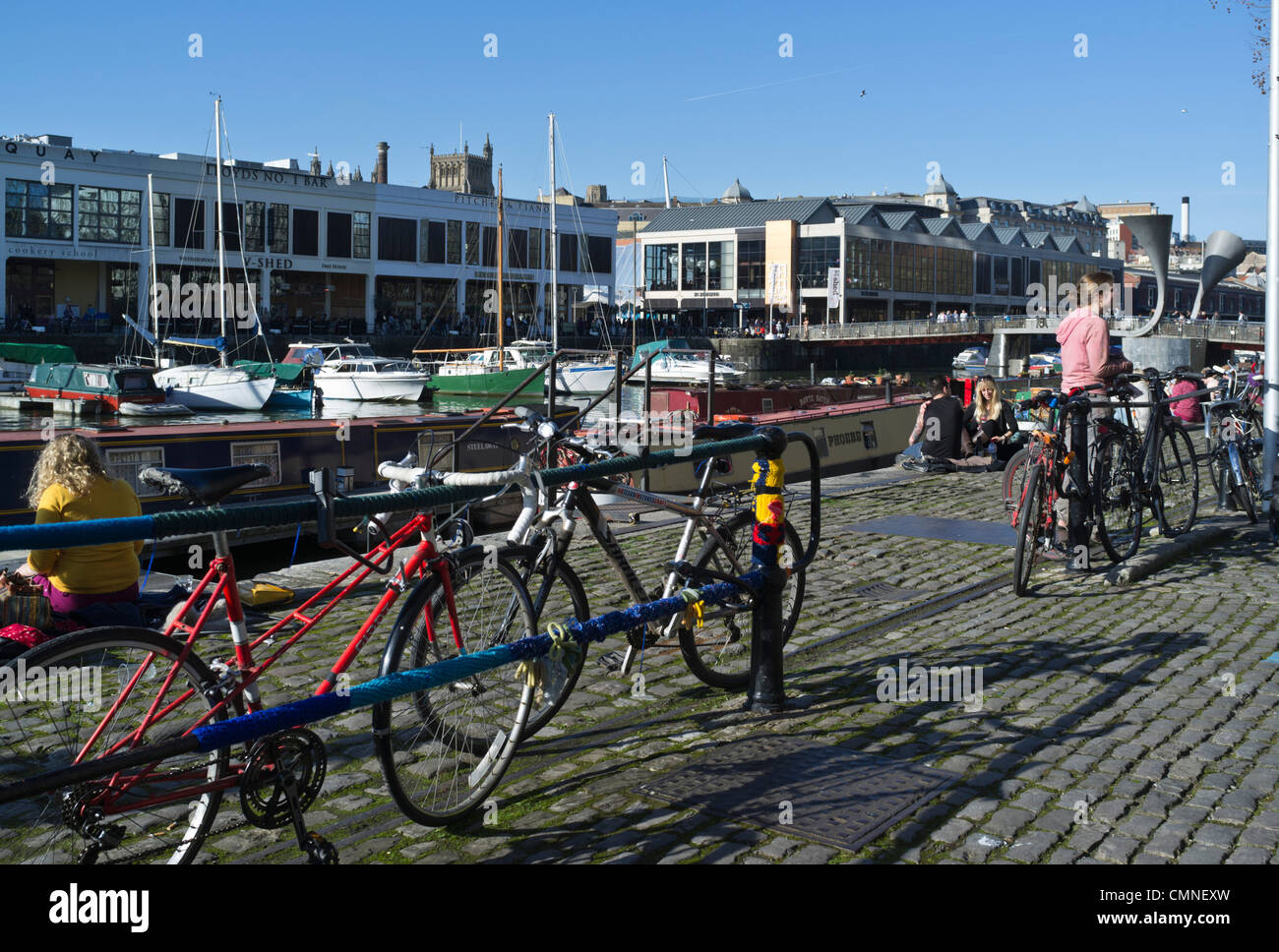 dh St Augustines erreichen BRISTOL DOCKS BRISTOL Cyclist Fahrräder geparkt Menschen entspannende Stadt Winter Sonnenschein Fahrrad Parken Fahrräder großbritannien Stockfoto