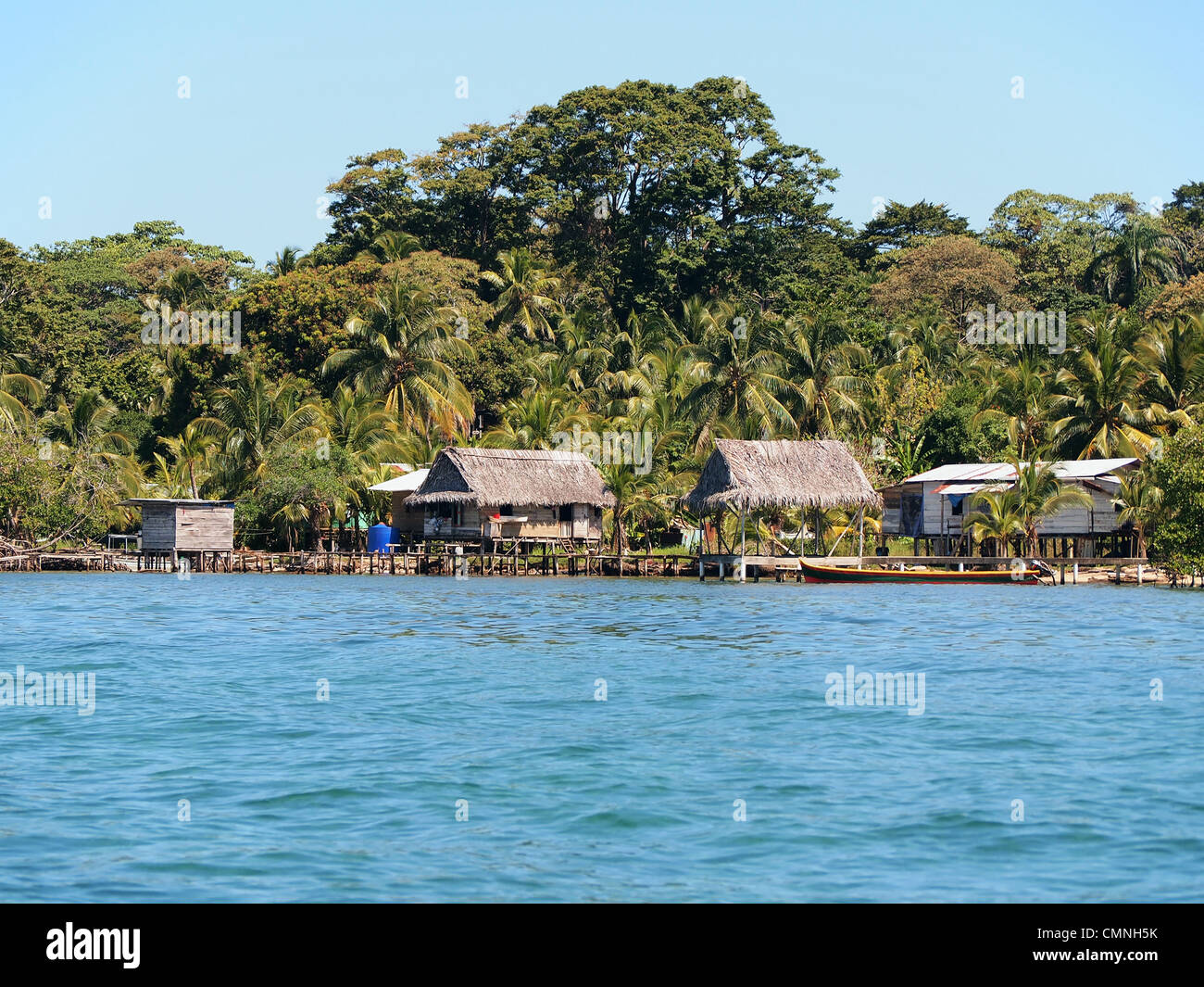 Rustikales haus mit strohgedeckten Hütte über Wasser und üppige tropische Vegetation an der karibischen Küste, Bocas del Toro, Panama, Mittelamerika Stockfoto