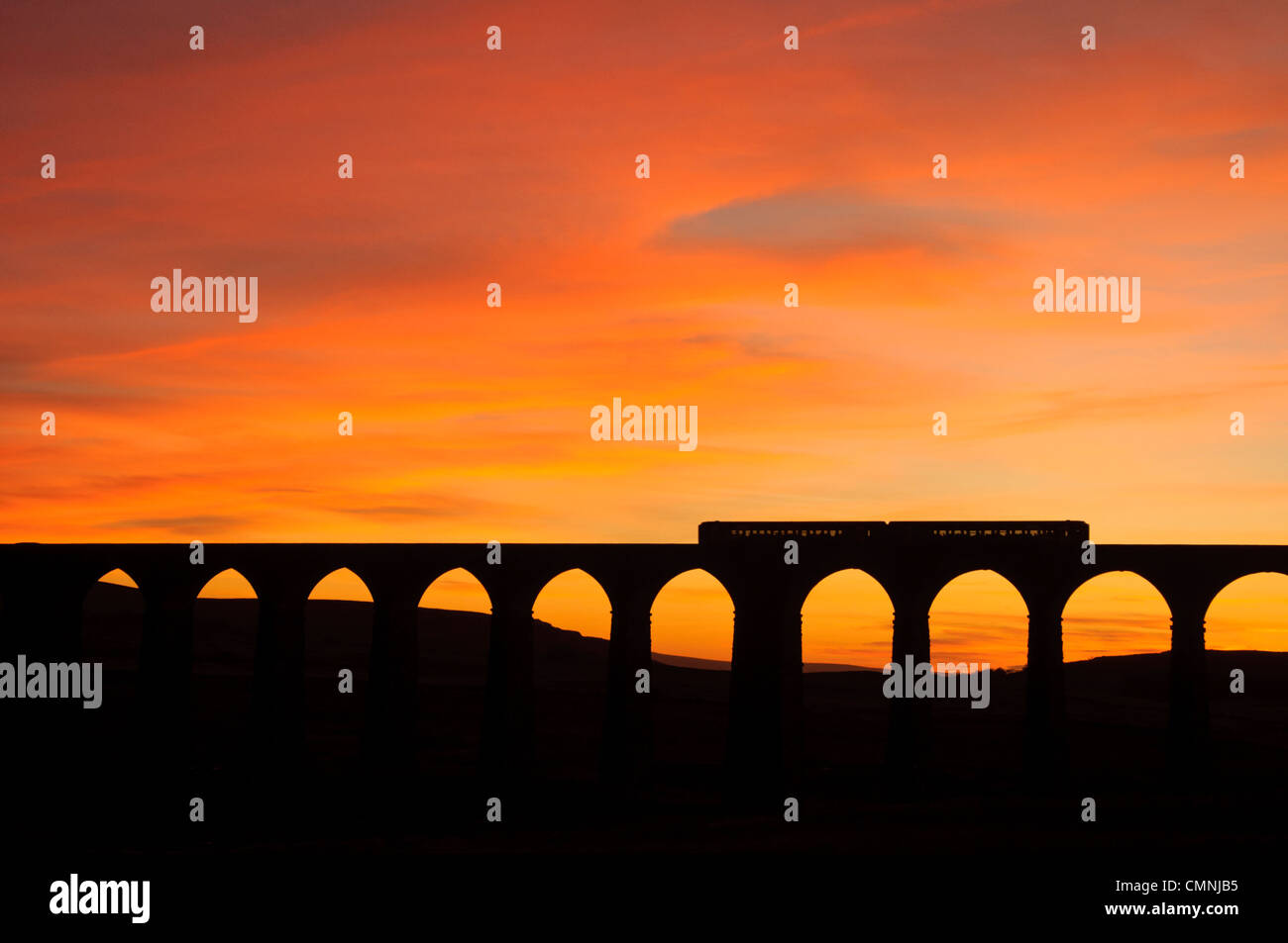Trainieren Sie auf dem Ribblehead-Viadukt an der Bahnstrecke Settle-Carlisle in der Yorkshire Dales National Park, England bei Sonnenuntergang Stockfoto