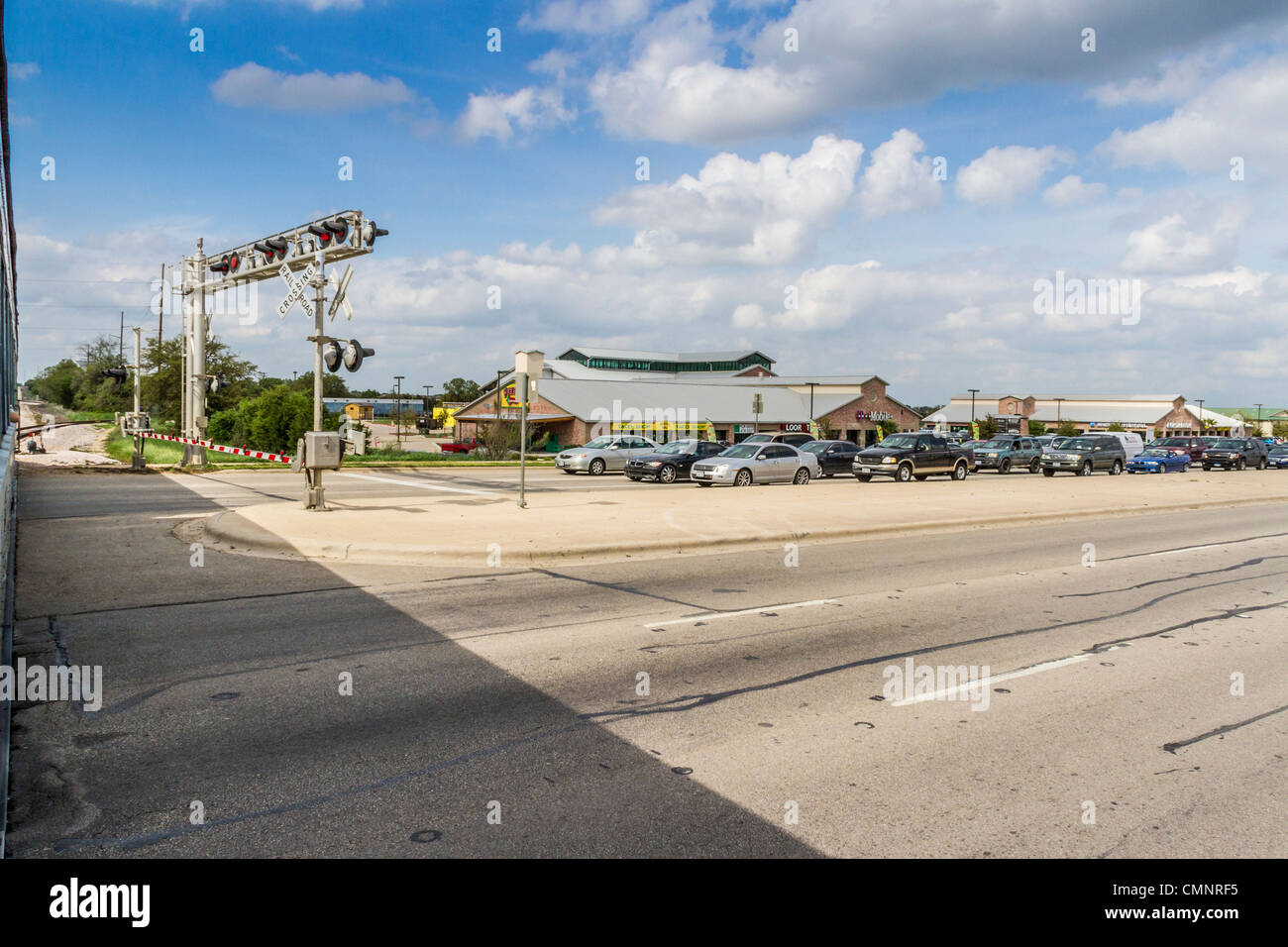 Autos warten an der Kreuzung auf den Zug, um den Touristenzug 'Hill Country Flyer' in Cedar Park, Texas (Vorort von Austin) zu passieren. Stockfoto