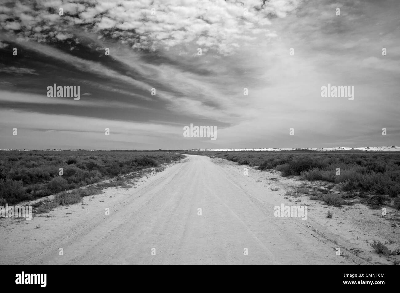 Outback-Straße mit weit entfernten Sanddünen unter Wüste Himmel Stockfoto