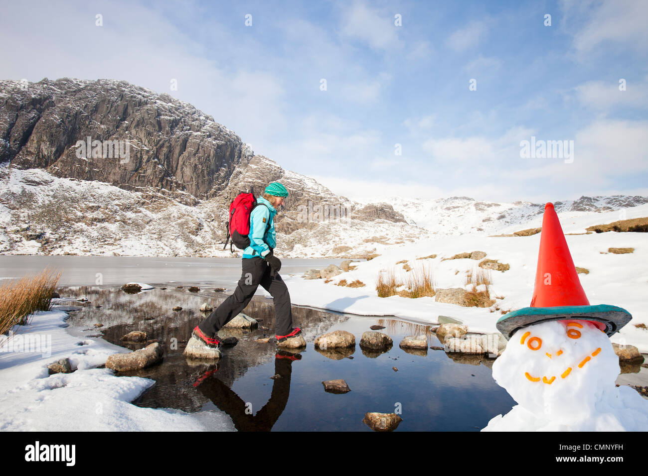 Frau Hill Wanderer durch eine gefrorene scheut Tarn in die saisonabhängige, Lake District, Großbritannien Stockfoto