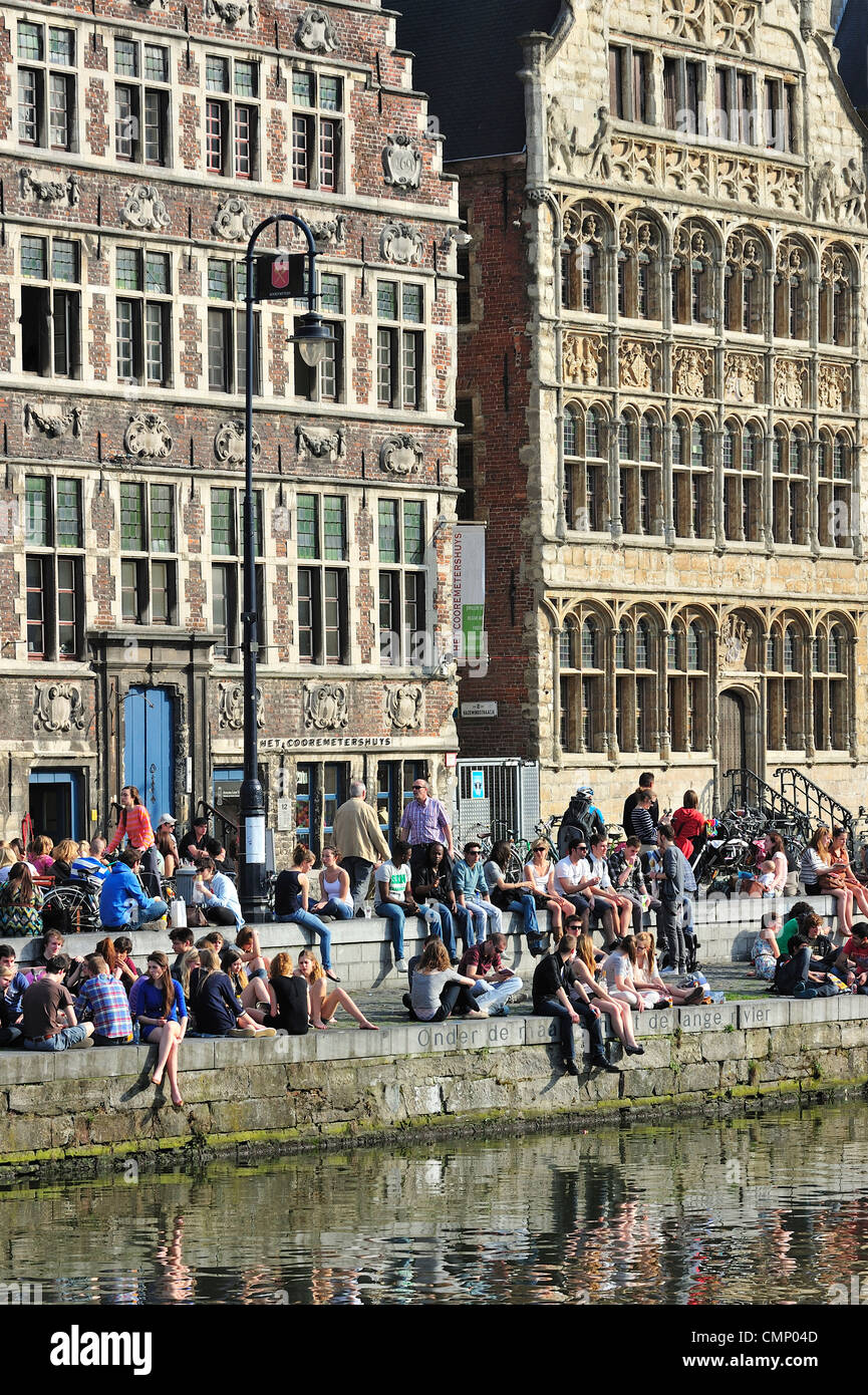 Touristen und Studenten genießen die erste Frühlingssonne am Wasser entlang der Graslei in Gent, Belgien Stockfoto