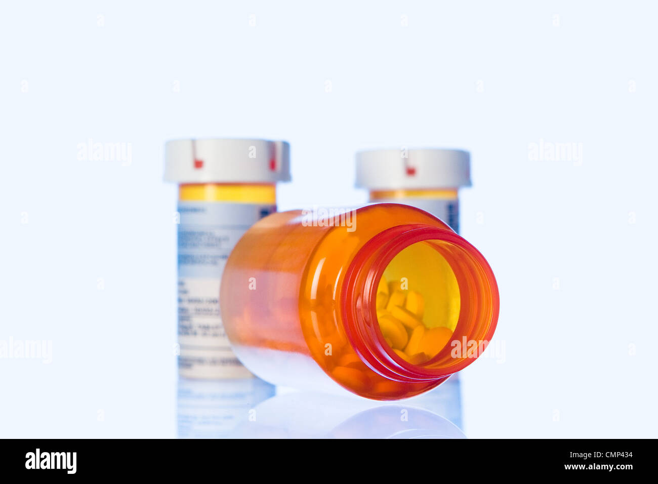 Drei Orangen Tablettenfläschchen Pulver Blau Licht auf transparente Oberfläche. Großen Vordergrund Flasche mit Pillen, verschlossen, stumme. Stockfoto