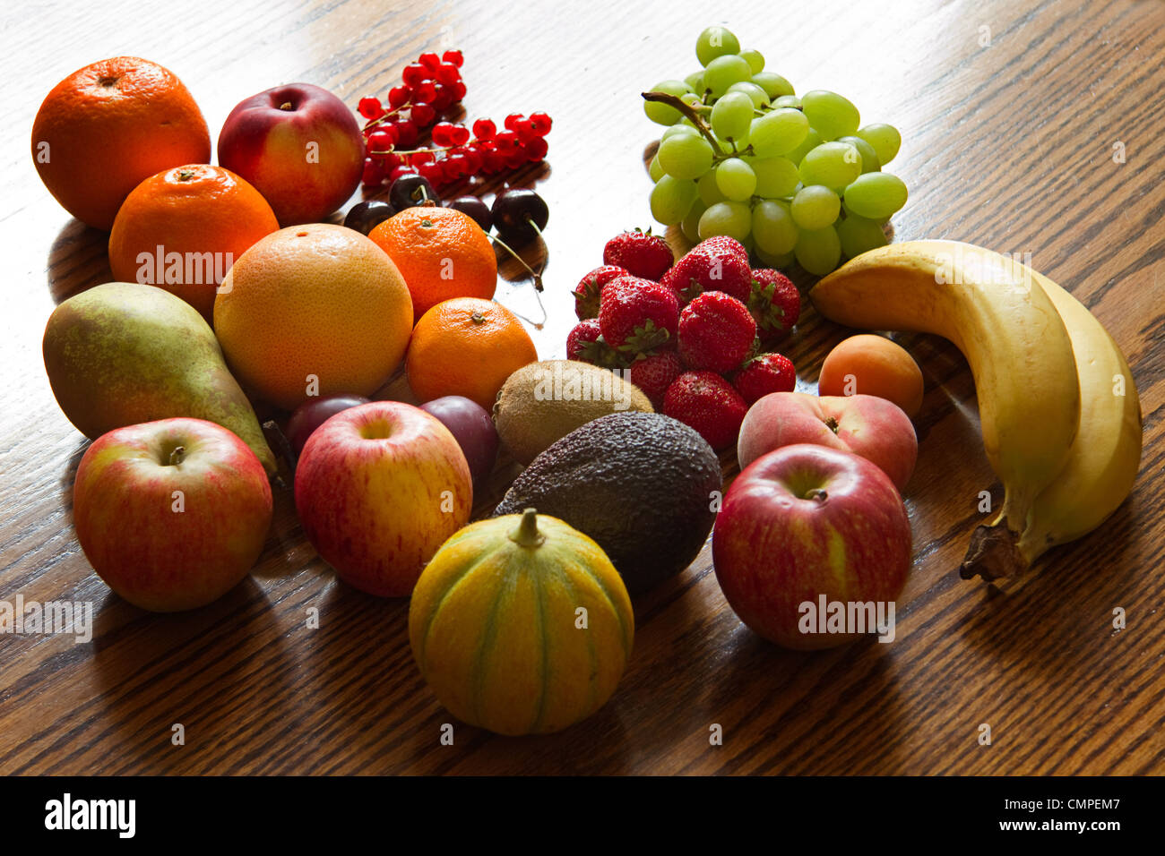 Auswahl an bunten, frischen, natürlichen aussehenden Früchten auf hölzernen Hintergrund mit Hintergrundbeleuchtung. Stockfoto