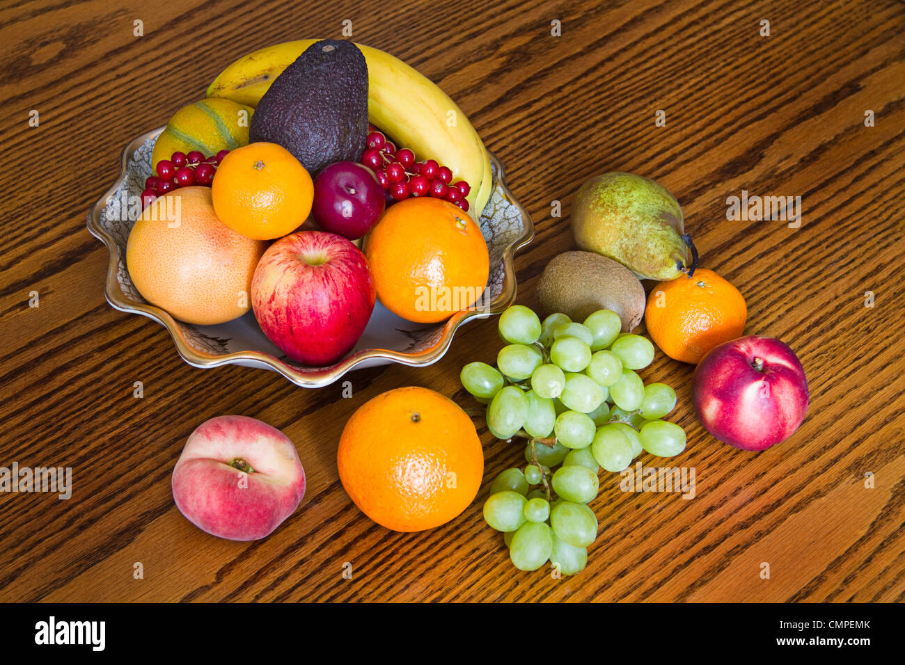 Auswahl an bunten, frischen, natürlichen aussehende Frucht in eine alte Schüssel auf hölzernen Hintergrund Stockfoto