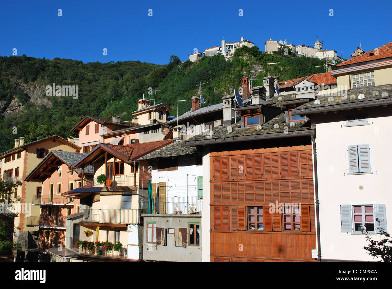 Typische Häuser auf Mastallone Fluss in Varallo Sesia, Sacred Mountain Sanctuary im Hintergrund, Piemont, Italien Stockfoto