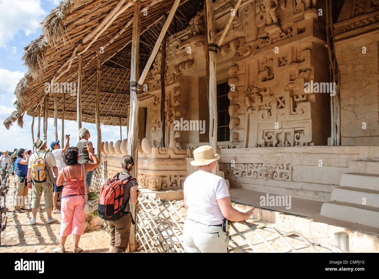 EK Balam Grab von Ukit Kan Lek Tok Fassade Mexiko // EKʼ BALAM, Mexiko - Besucher beobachten die aufwändig geschnitzte Fassade des Grabes von Ukit Kan Le'k Tok' auf der Akropolis in Ekʼ Balam (auch bekannt als Ek Balam) archäologische Stätte. Das gut erhaltene spätklassizistische Gebäude verfügt über aufwändige Kalksteinschnitzereien, darunter die charakteristischen jaguar Motive und einzigartige geflügelte Figuren. Das Grab stellt eines der schönsten Beispiele der architektonischen Skulptur der Maya in der nördlichen Yucatan-Region dar. Ukit Kan Le'k Tok' regierte das alte Königreich Talol ab 770-797 n. Chr. und ließ dieses monumentale in Betrieb nehmen Stockfoto