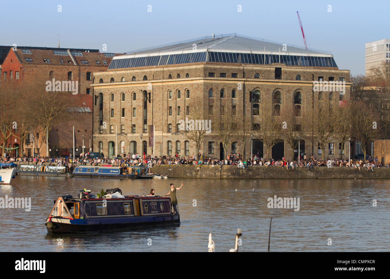 Menschen genießen die Sonne auf das Harbourside außerhalb Arnolfini Galerie in Bristol. Das Zentrum ist ein kultureller Hotspot der Stadt. Stockfoto