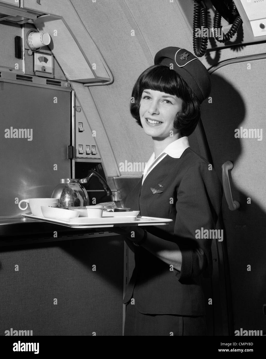 1960ER JAHREN LÄCHELND FLUGBEGLEITERIN HOLDING TABLETT MIT KAFFEE SERVICEARTIKEL Stockfoto