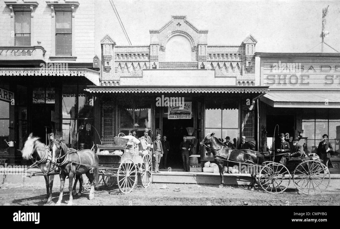 1880S 1885 MÄNNER STEHEN NEBEN PFERD GEZEICHNET WAGEN VOR DEN GESCHÄFTEN AUF DER NORDSEITE DES COLORADO STREET PASADENA KALIFORNIEN USA Stockfoto