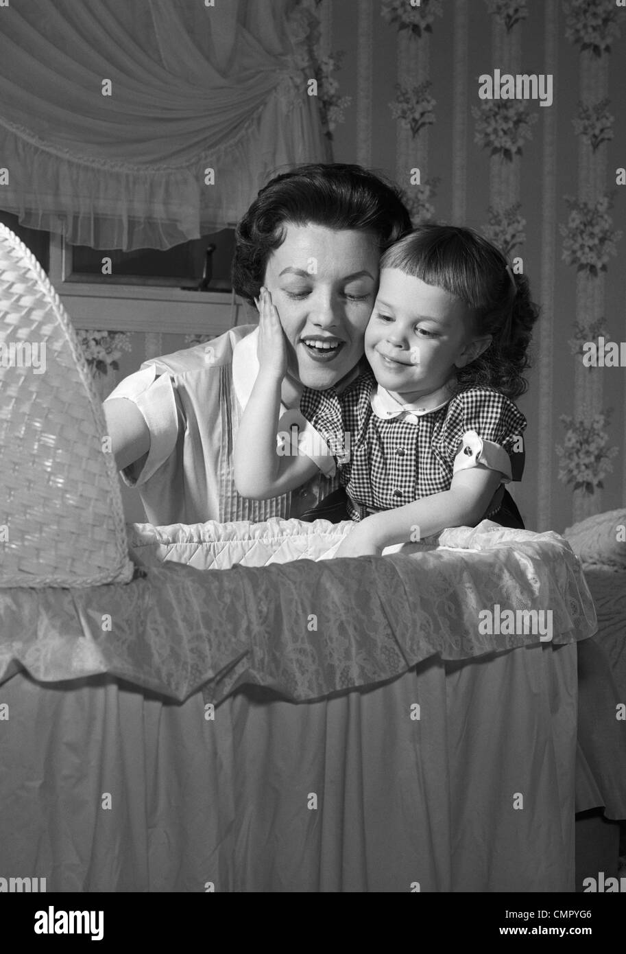 1950ER JAHRE BABY MUTTER & TOCHTER BEWUNDERN IN WIEGE Stockfoto