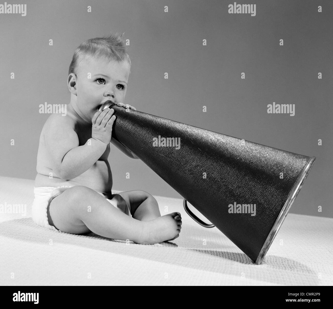 1960ER JAHRE BABY IN WINDELN SITZEN HOLDING MEGAPHON Stockfoto