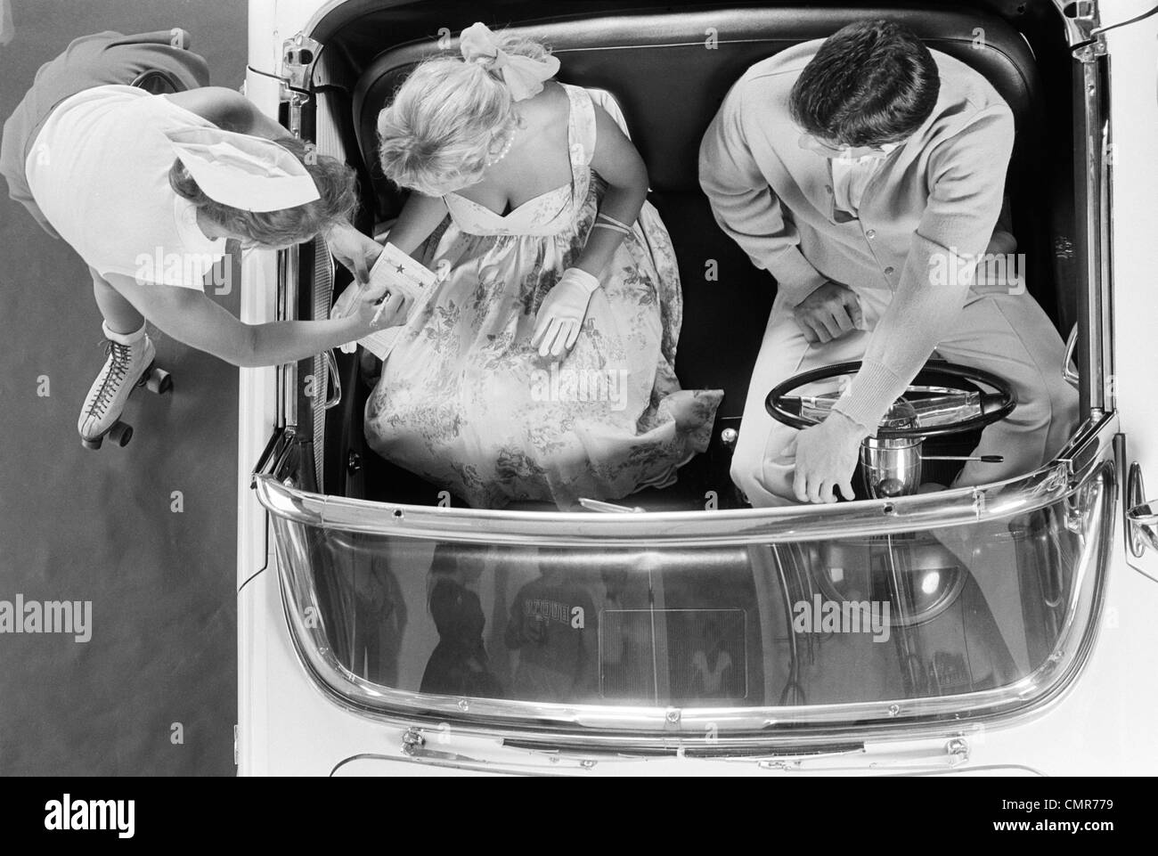 1950S 1960S LUFTBILD VON CARHOP AUF ROLLSCHUHEN NEHMEN BESTELLUNG VON PAAR IN CABRIO AUTO Stockfoto
