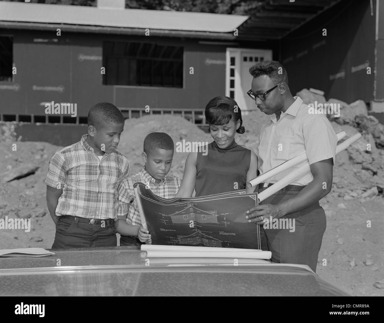 1960ER JAHREN AFROAMERIKANISCHE FAMILIE AUSSEHENDE AT BAUPLÄNE HAUS NEUBAU Stockfoto