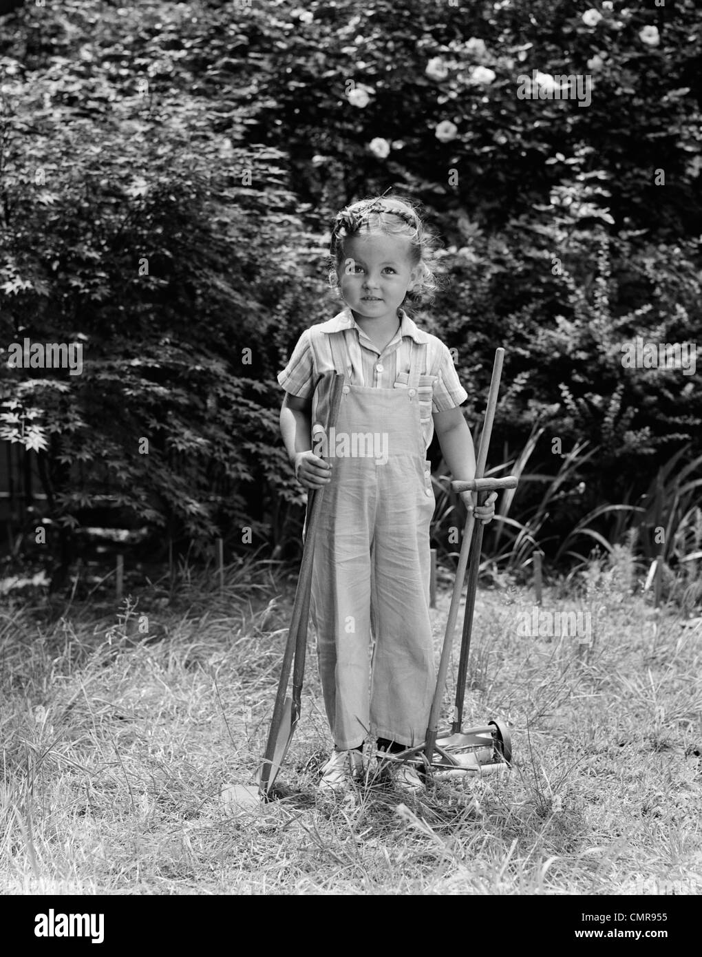 1940ER JAHRE KIND HOLDING RASEN TOOLS FUNKTIONIEREN KLEIDUNG GRASS Stockfoto