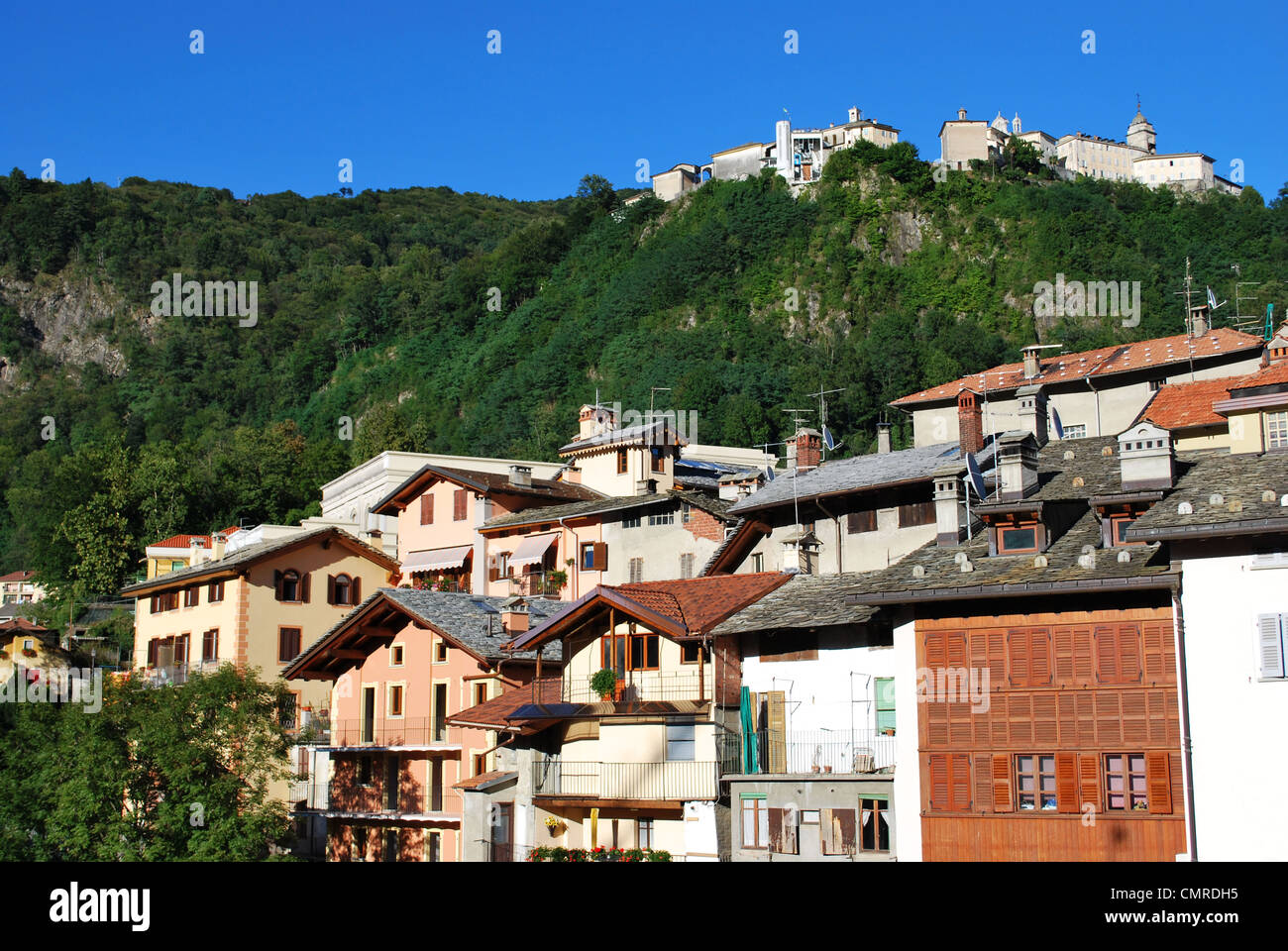 Typische Häuser auf Mastallone Fluss in Varallo Sesia, Sacred Mountain Sanctuary im Hintergrund, Piemont, Italien Stockfoto