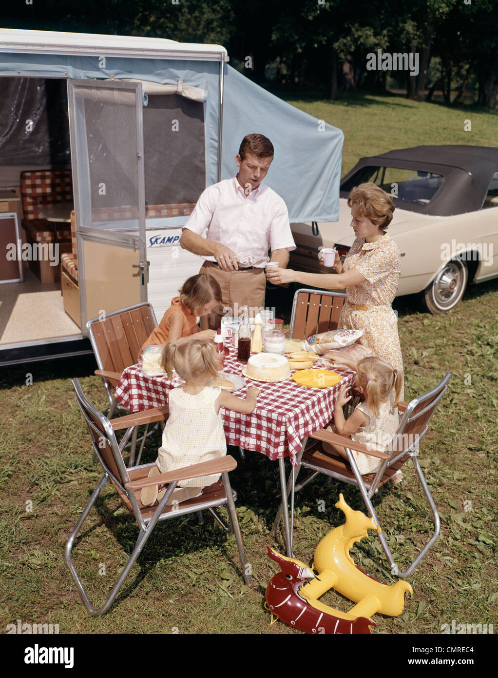 1960ER JAHRE FAMILIE VATER MUTTER DREI TÖCHTER ESSEN VON RV CAMPER Stockfoto