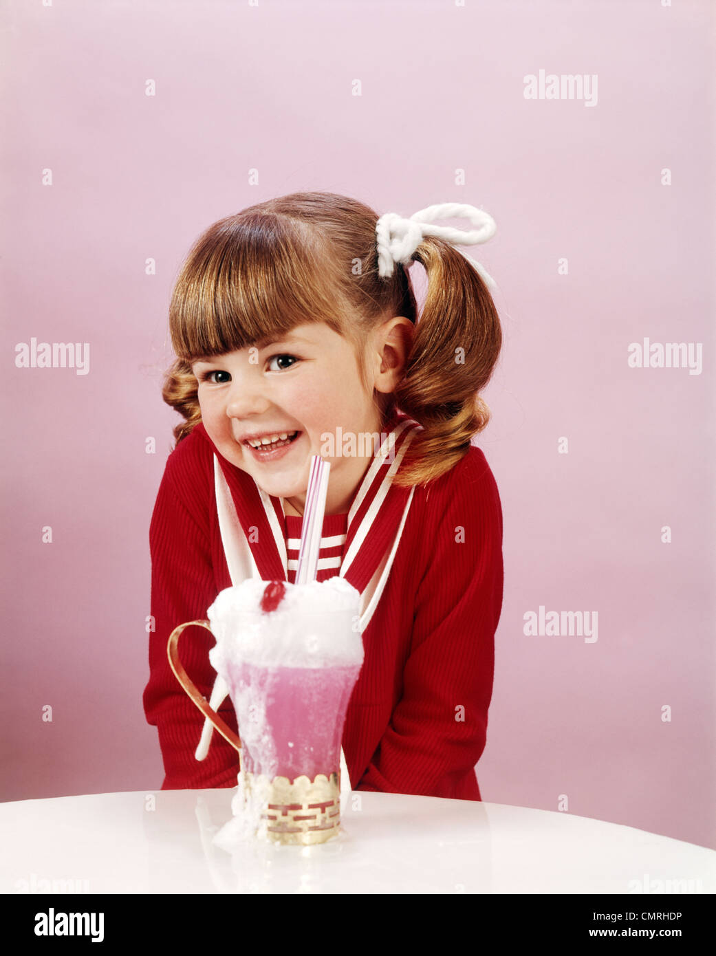 1960ER JAHRE 19670S HAPPY LITTLE GIRL WITH ICE CREAM SODA STUDIO PFERDESCHWANZ Stockfoto