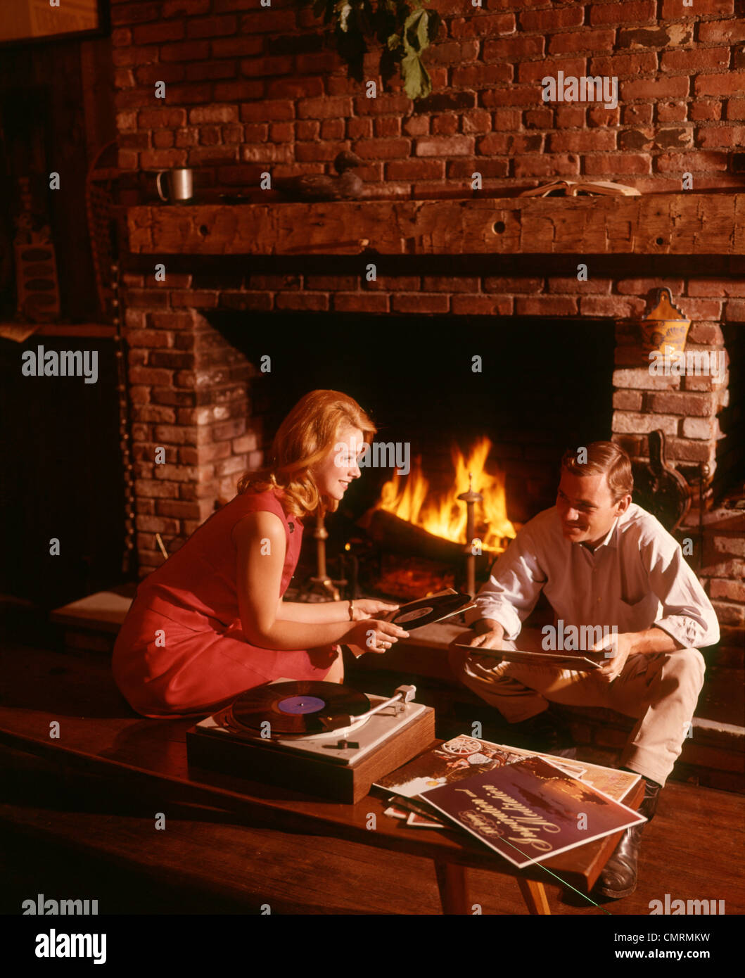 1960 DER 1960ER JAHRE 1970 1970ER JAHRE PAAR MANN FRAU WOHNZIMMER KAMIN SCHALLPLATTEN PLATTENSPIELER STEREO-HI FI MUSIK VINYL RETRO Stockfoto