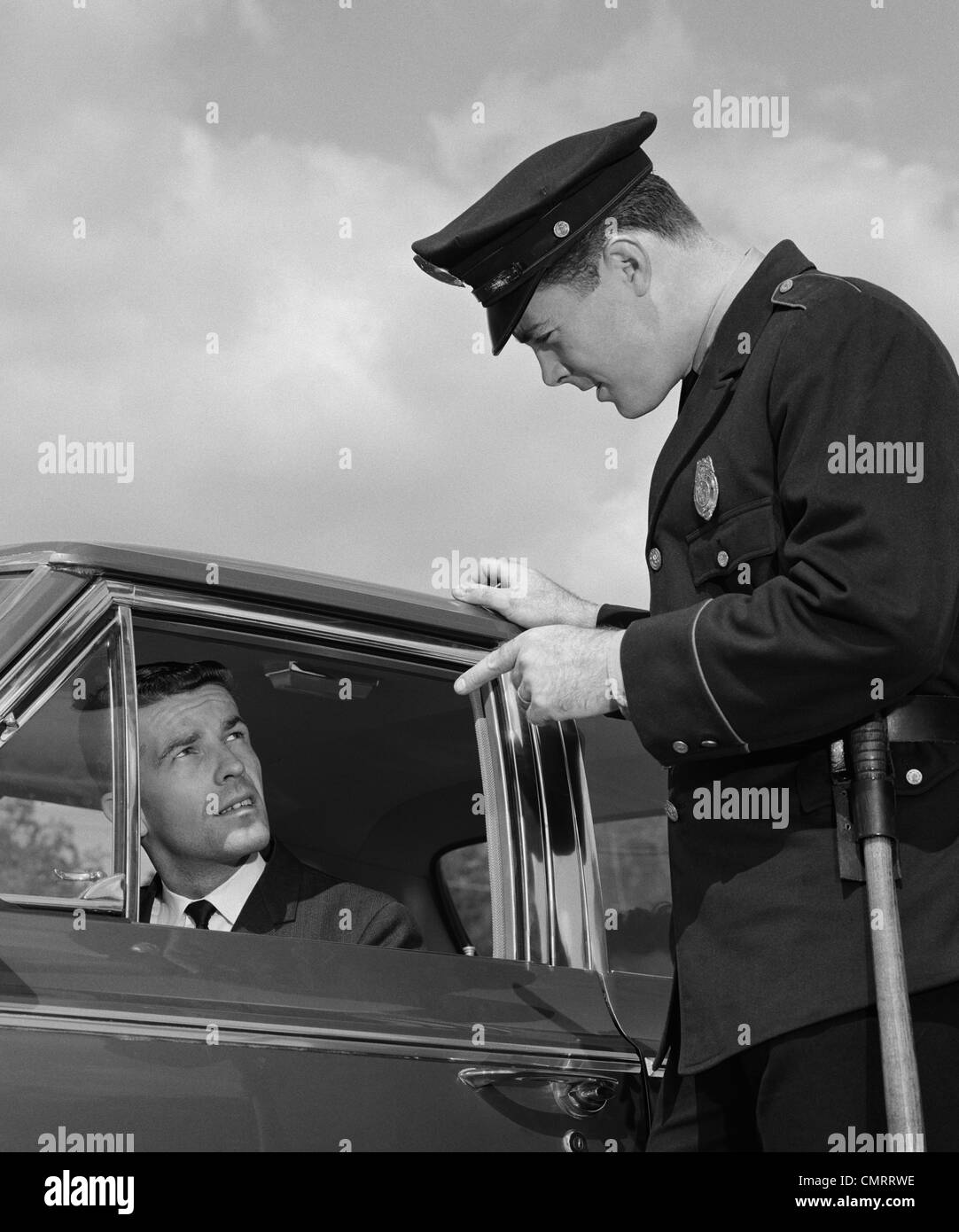 1960ER JAHREN POLIZIST WARNUNG AUTOFAHRER ZEIGT FINGER AUF TREIBER Stockfoto