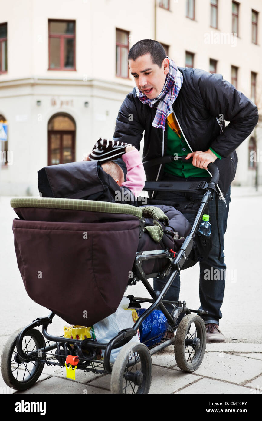 Vater mit Baby (0-11 Monate) Kinderwagen gegen Bauwerke Stockfoto