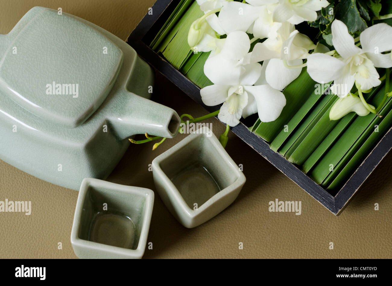 Thailand, Bangkok. Traditionelle Thai Teekanne und Tassen mit Orchidee Anordnung. Stockfoto
