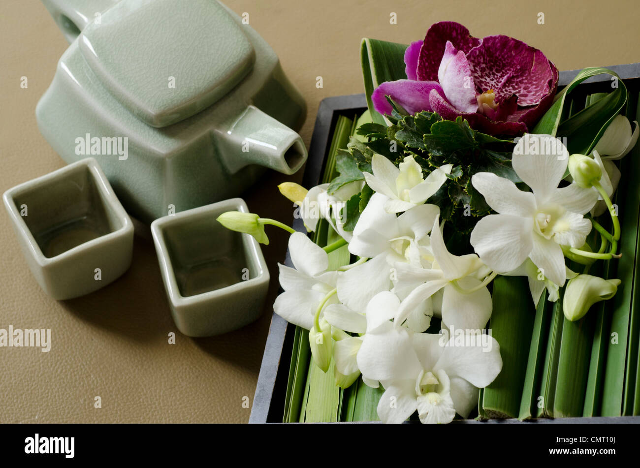 Thailand, Bangkok. Traditionelle Thai Teekanne und Tassen mit Orchidee Anordnung. Stockfoto