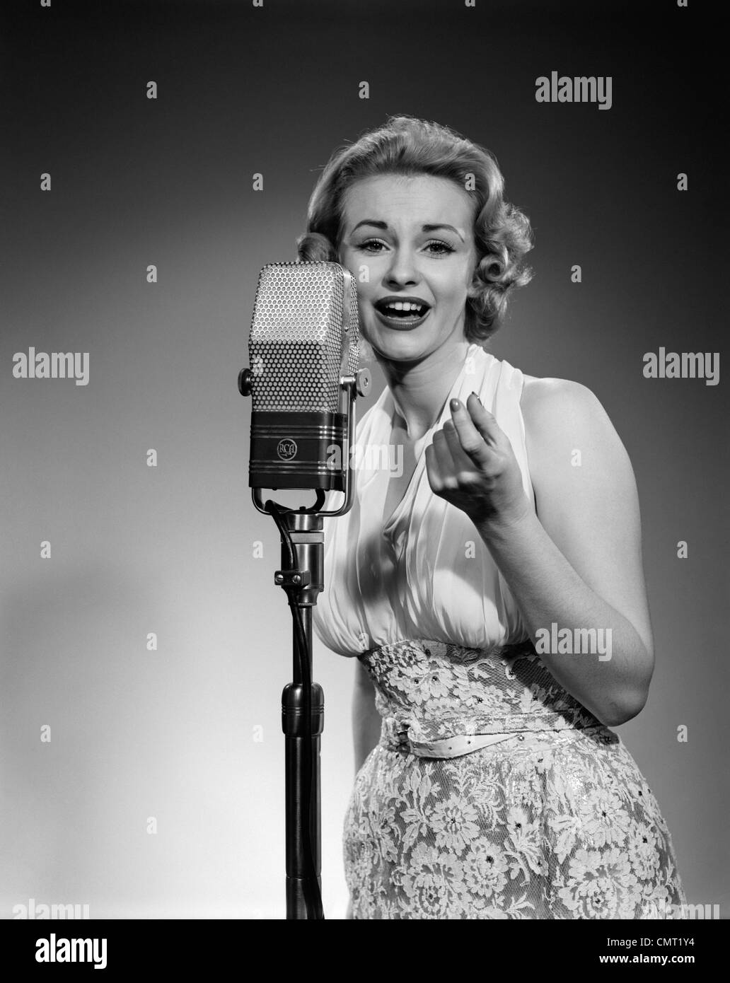 1950ER JAHRE PORTRAIT FRAU ENTERTAINER SINGEN IN EIN MIKROFON STUDIO BLICK IN DIE KAMERA Stockfoto