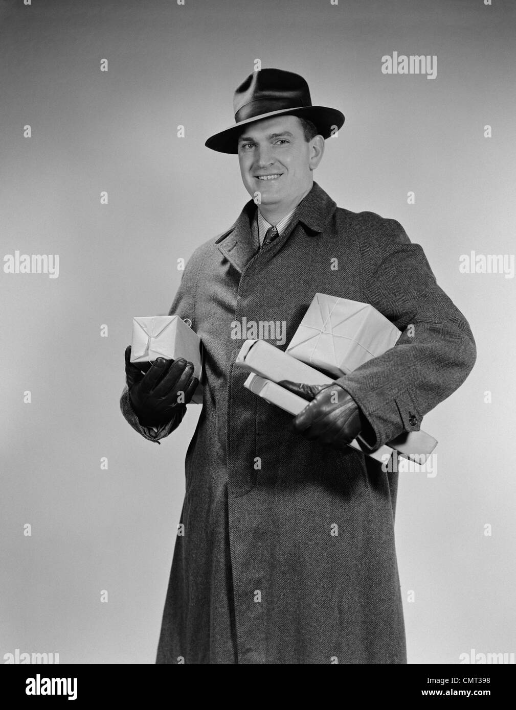 1940ER JAHRE MANN TRAGEN FELL MÜTZE HANDSCHUHE HOLDING PAKETE PAKETE Stockfoto