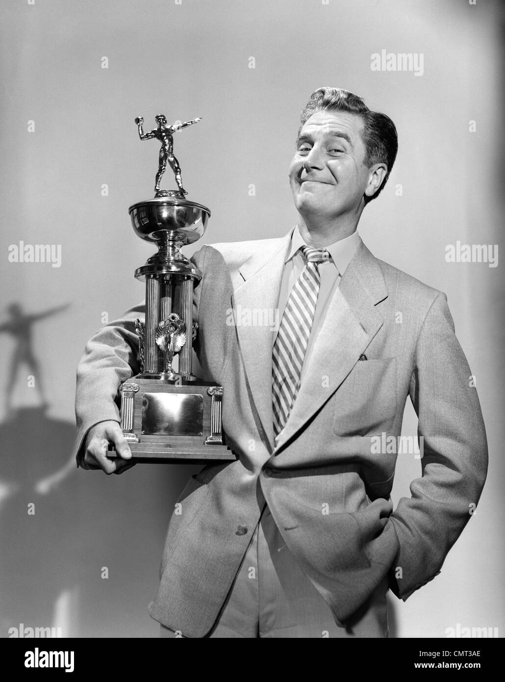1950S 1960S STOLZER MANN LÄCHELND, EINE FUßBALL-TROPHÄE BLICK IN DIE KAMERA HALTEN Stockfoto