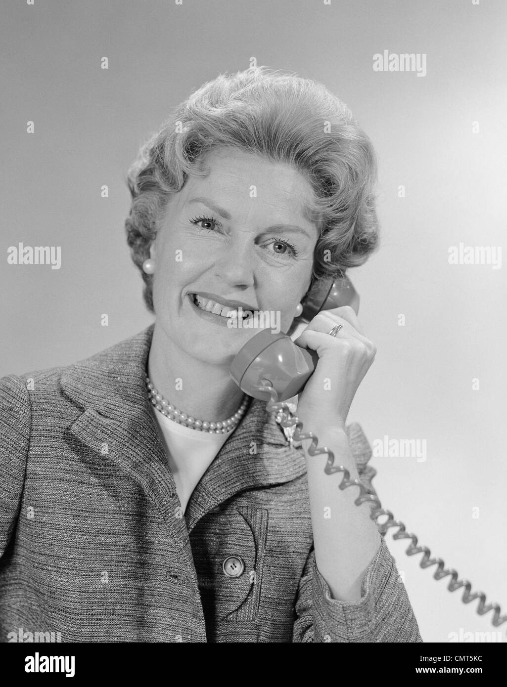 1960ER JAHRE PORTRAIT LÄCHELND REIFE FRAU AM TELEFON SPRECHEN Stockfoto