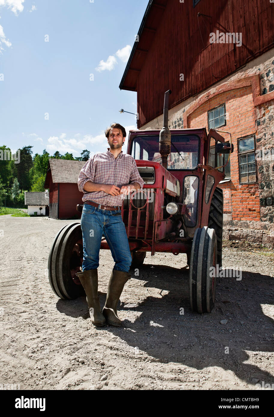 Gesamte Länge der Landwirt stützte sich auf Traktor und wegsehen Stockfoto