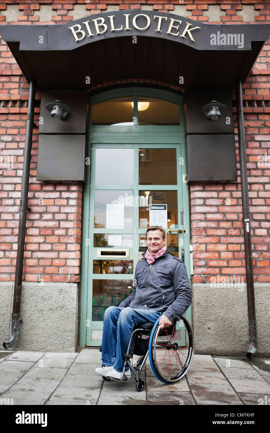 Mann im Rollstuhl sitzen außerhalb der Bibliothek Stockfoto