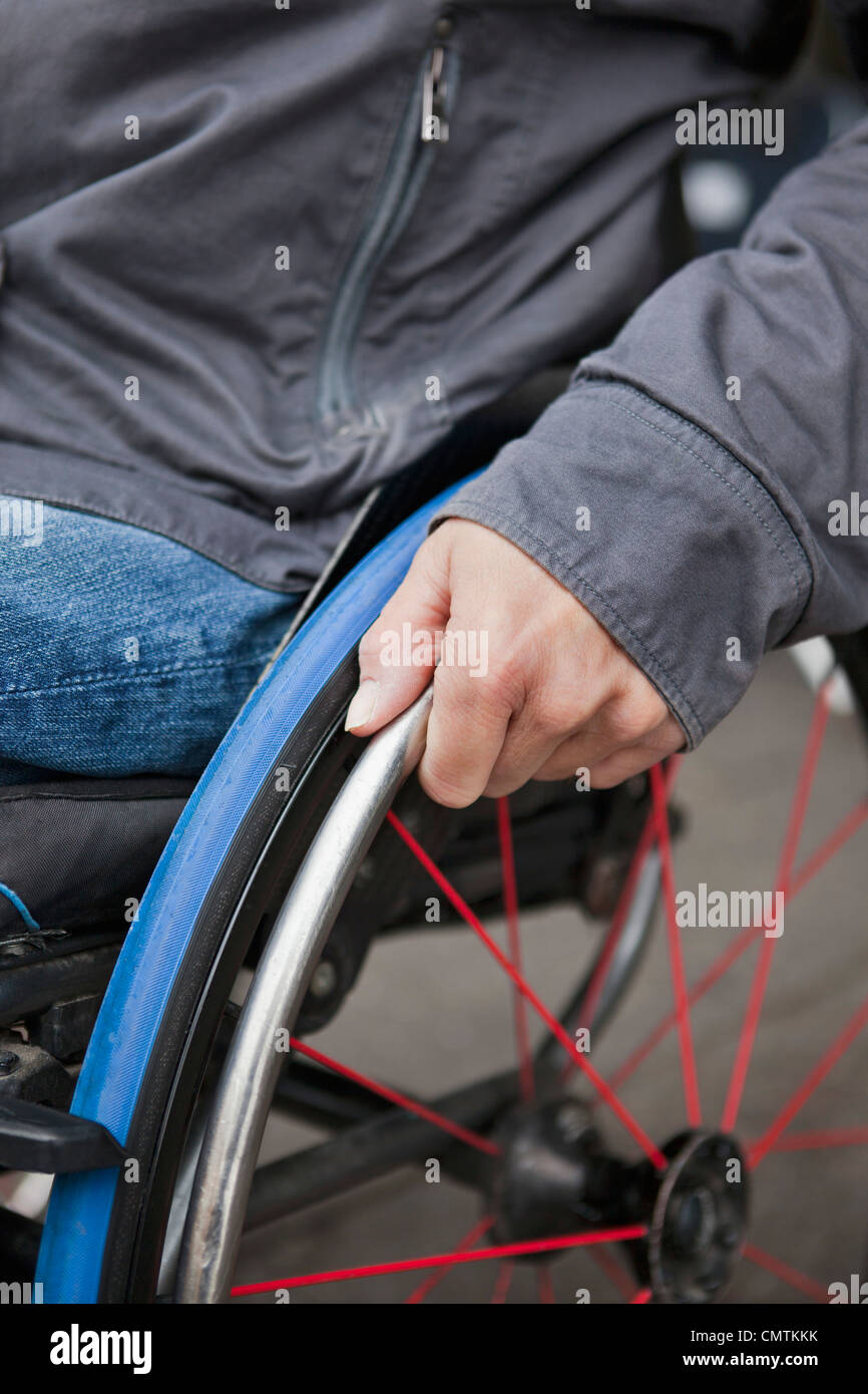 Die Hand des Mannes auf Rollstuhl-Rad Stockfoto