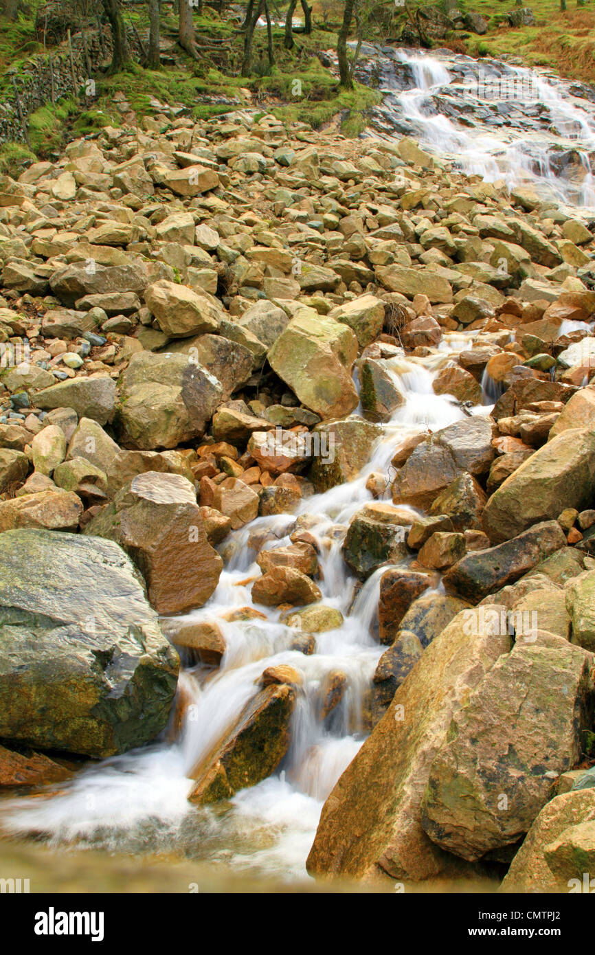 Wasser fließt durch Felsen in Buttermere-See in der Seenplatte, Cumbria, England UK Stockfoto