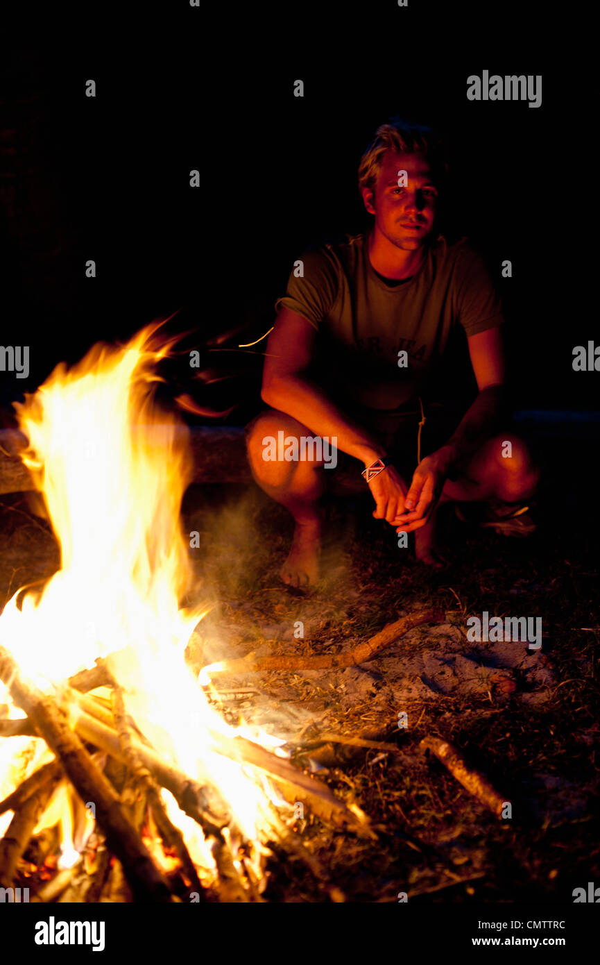 Mann sitzt neben Feuer Stockfoto