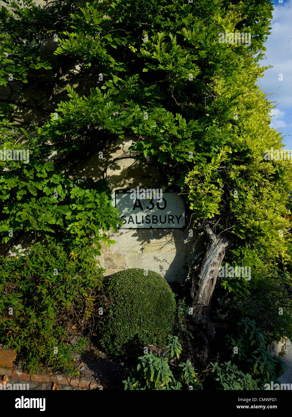 Englisch British Land A30 Salisbury Straßenschild auf Mauerbau mit viel Grün und Pflanzen Stockfoto