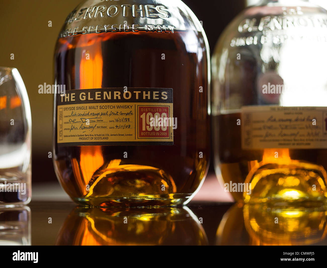 zwei Flaschen Whisky mit Glas am Tisch in einem Raum Stockfoto