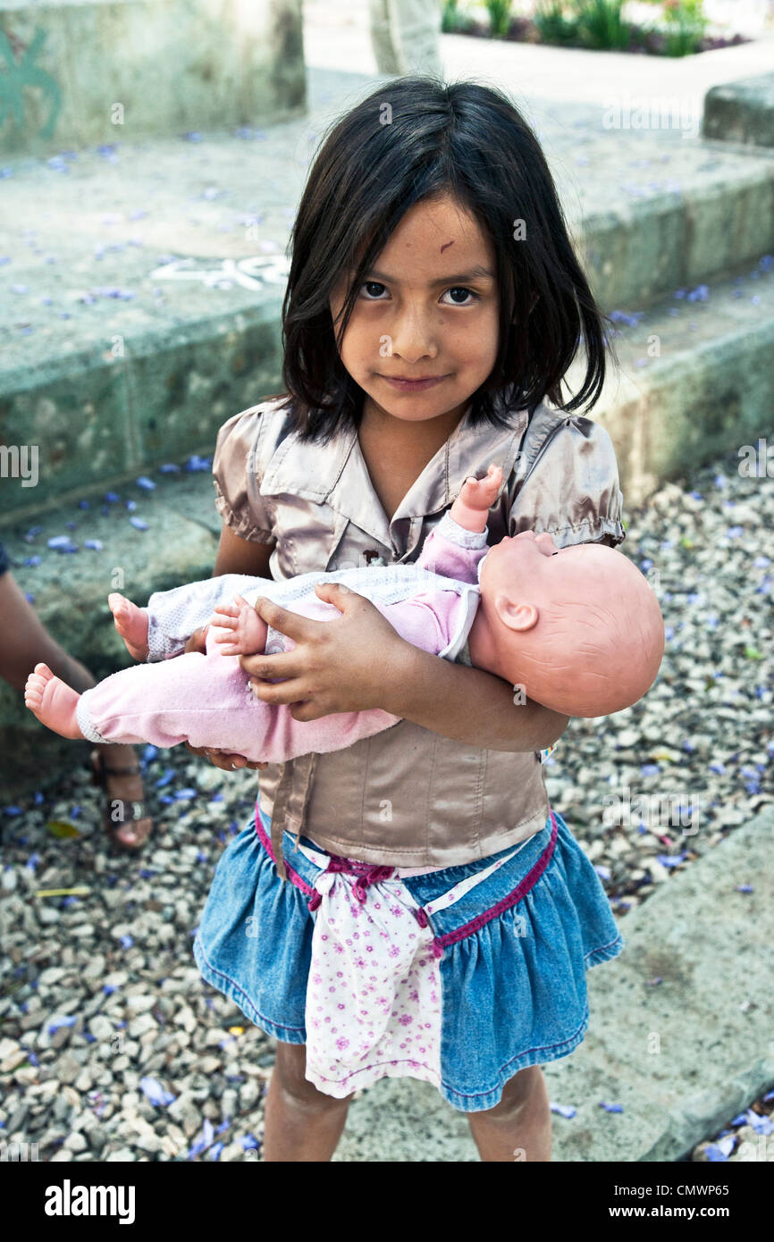 kleine süße schüchtern lächelnde einheimische mexikanische Inderin mit Schorf auf Stirn hält schüchtern ihre lebensechten Kunststoff Baby-Puppe Oaxaca Stockfoto