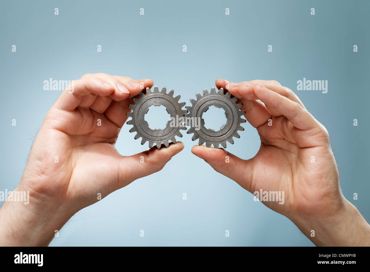 Ein Mann hält ein übereinstimmendes paar alte cog Zahnräder in seinen Händen. Stockfoto