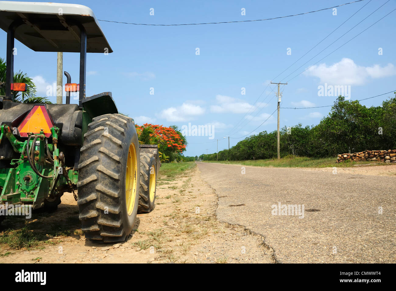 Ein Traktor geparkt an der Seite einer leeren Straße von hinten betrachtet. Stockfoto