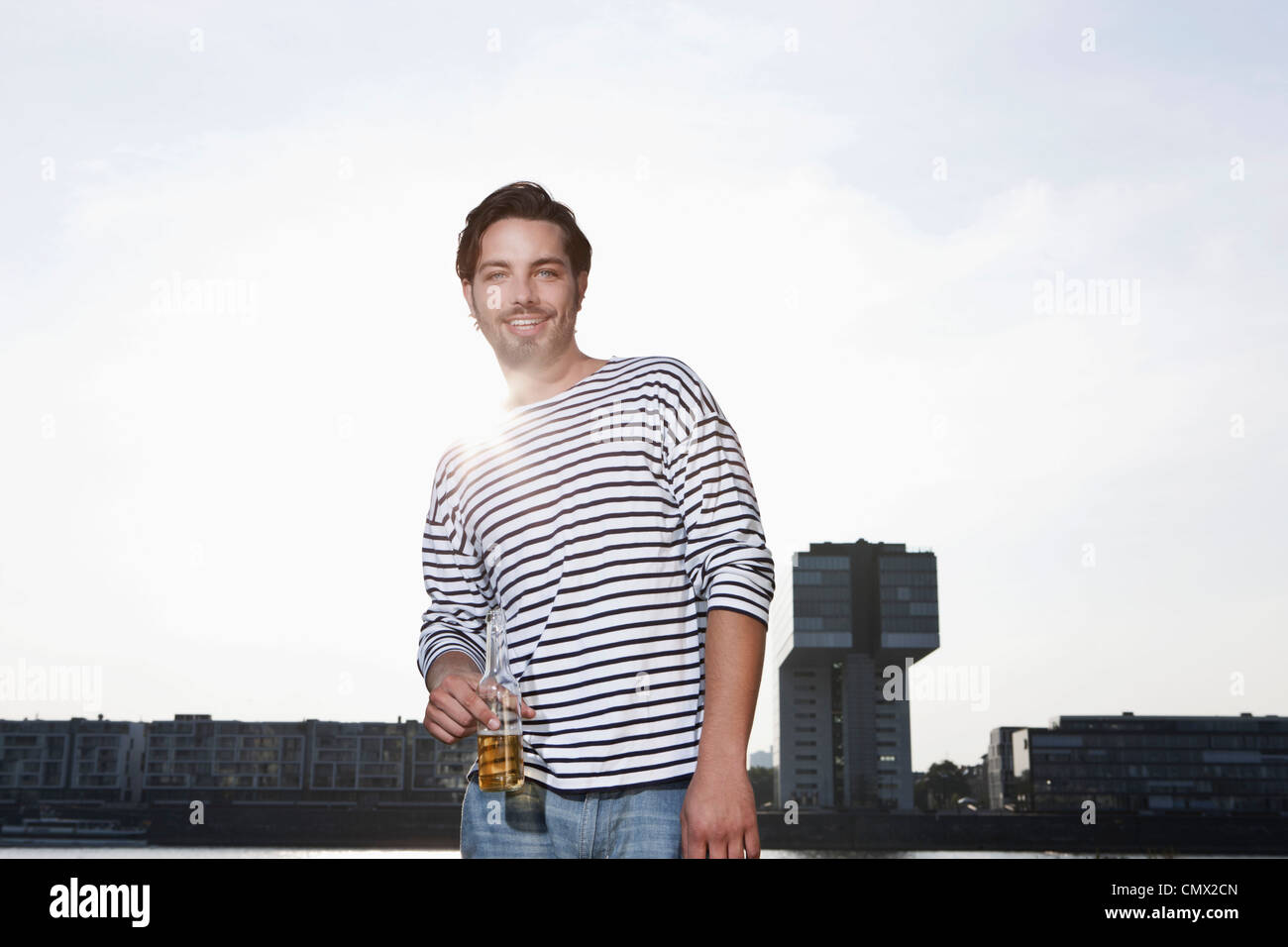Deutschland, Köln, junger Mann mit Bierflasche, Lächeln, Porträt Stockfoto