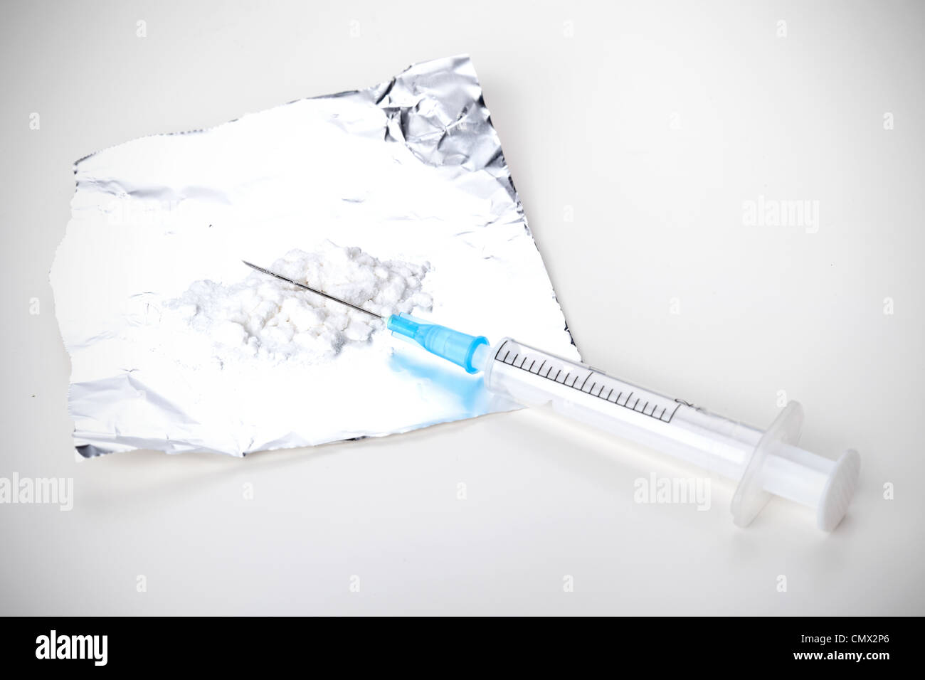 Spritze und Heroin auf Folie, Closeup auf weißem Hintergrund Stockfoto