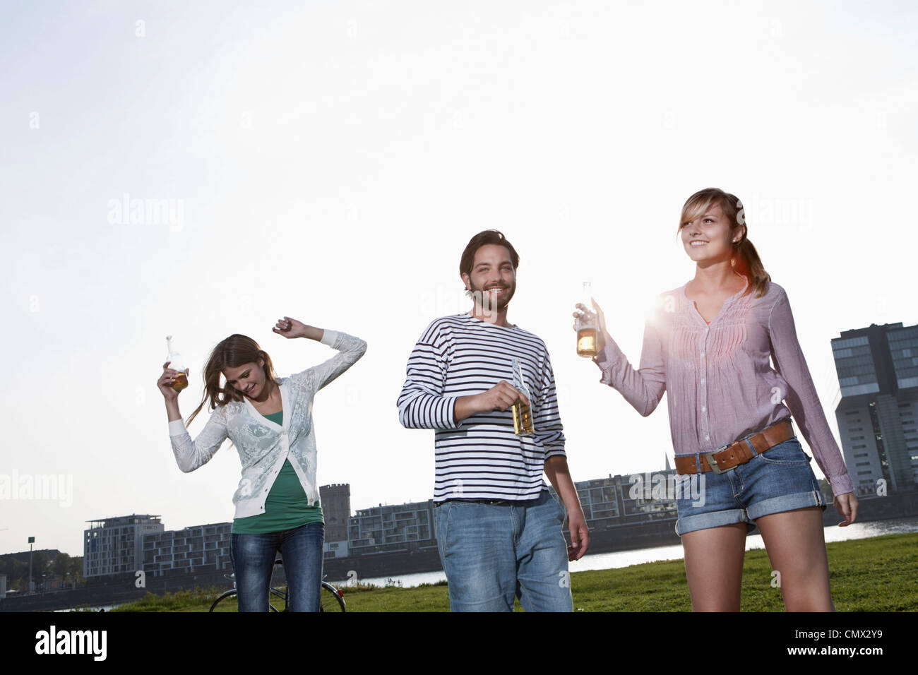 Deutschland, Köln, junger Mann und Frau tanzt mit Bierflaschen, Lächeln Stockfoto