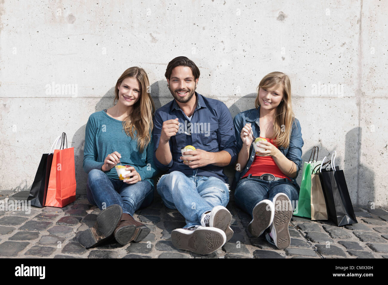 Deutschland, Köln, junger Mann und mit Eis und Einkaufstaschen, Lächeln, Porträt Stockfoto